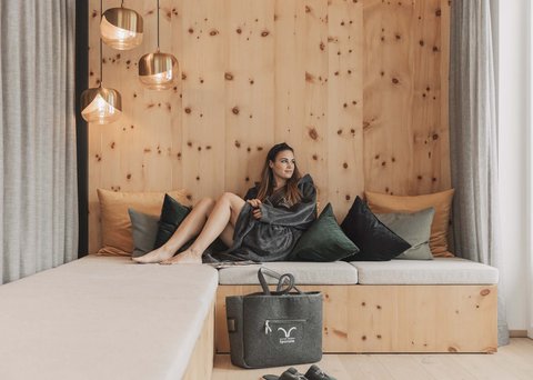 Pictures from Sportalm Woman relaxing on wooden couch with pillows and hanging lamps