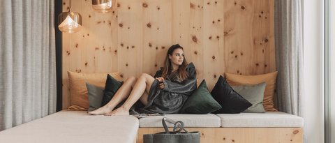 Pictures from Sportalm Woman relaxing on wooden couch with pillows and hanging lamps