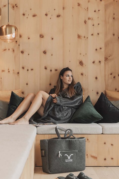 Pictures from Sportalm Woman relaxing on wooden couch with pillows and hanging lamps