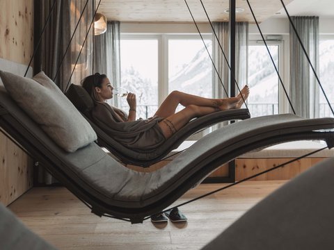 Bilder aus der Sportalm Frau entspannt auf hängender Liege im Wellnessbereich mit Bergblick