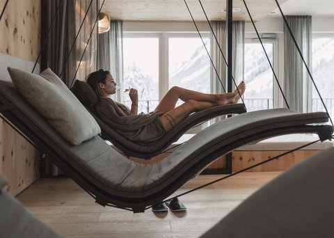 Bilder aus der Sportalm Frau entspannt auf hängender Liege im Wellnessbereich mit Bergblick