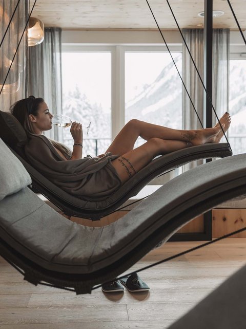 Bilder aus der Sportalm Frau entspannt auf hängender Liege im Wellnessbereich mit Bergblick