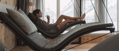 Bilder aus der Sportalm Frau entspannt auf hängender Liege im Wellnessbereich mit Bergblick