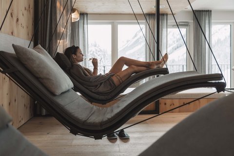 Bilder aus der Sportalm Frau entspannt auf hängender Liege im Wellnessbereich mit Bergblick
