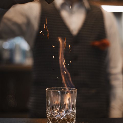 Pictures from Sportalm Bartender sprinkles spice on flaming drink in glass
