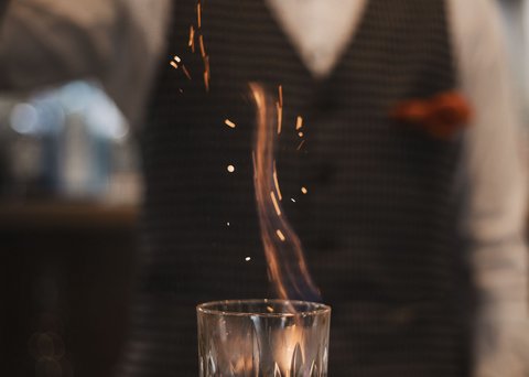 Bilder aus der Sportalm Barkeeper streut Gewürz auf brennenden Drink im Glas