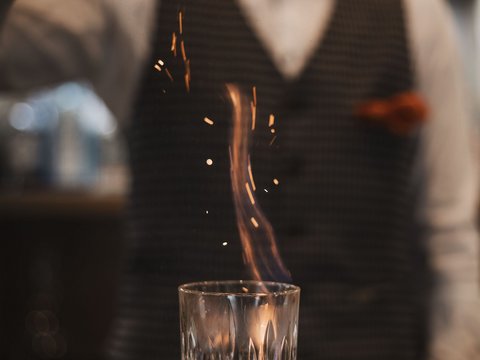 Pictures from Sportalm Bartender sprinkles spice on flaming drink in glass