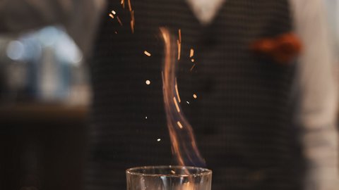 Bilder aus der Sportalm Barkeeper streut Gewürz auf brennenden Drink im Glas