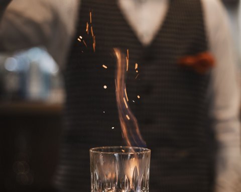 Bilder aus der Sportalm Barkeeper streut Gewürz auf brennenden Drink im Glas