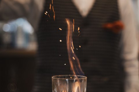 Pictures from Sportalm Bartender sprinkles spice on flaming drink in glass