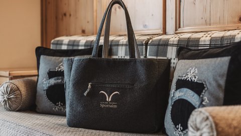 Bilder aus der Sportalm Filztasche mit Alpenresort Sportunkl-Logo auf gemütlicher Couch