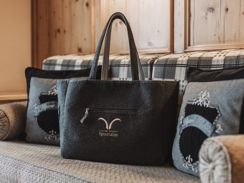 Bilder aus der Sportalm Filztasche mit Alpenresort Sportunkl-Logo auf gemütlicher Couch