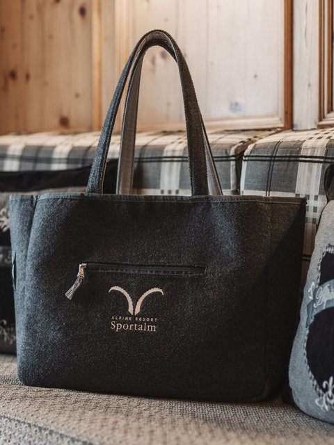 Bilder aus der Sportalm Filztasche mit Alpenresort Sportunkl-Logo auf gemütlicher Couch
