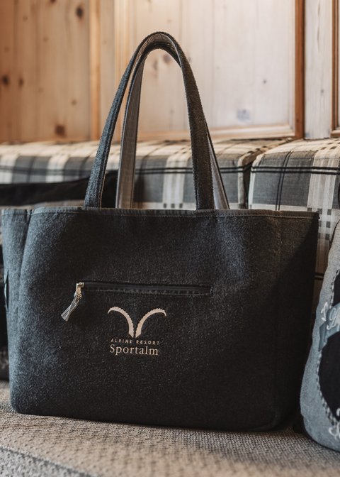 Bilder aus der Sportalm Filztasche mit Alpenresort Sportunkl-Logo auf gemütlicher Couch
