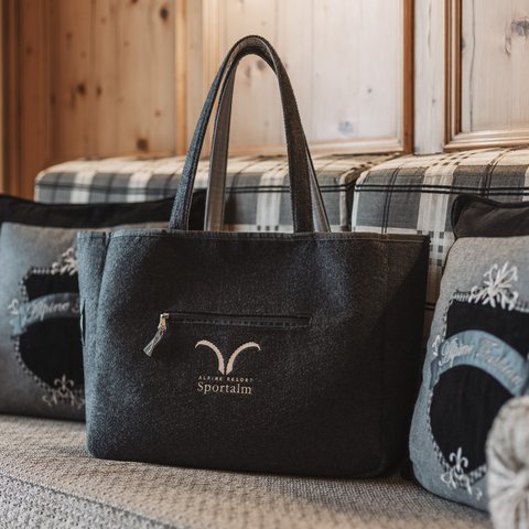 Bilder aus der Sportalm Filztasche mit Alpenresort Sportunkl-Logo auf gemütlicher Couch