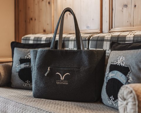 Bilder aus der Sportalm Filztasche mit Alpenresort Sportunkl-Logo auf gemütlicher Couch