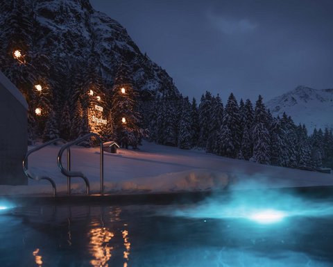 Bilder aus der Sportalm Beleuchteter Außenpool bei Nacht in verschneiter Berglandschaft