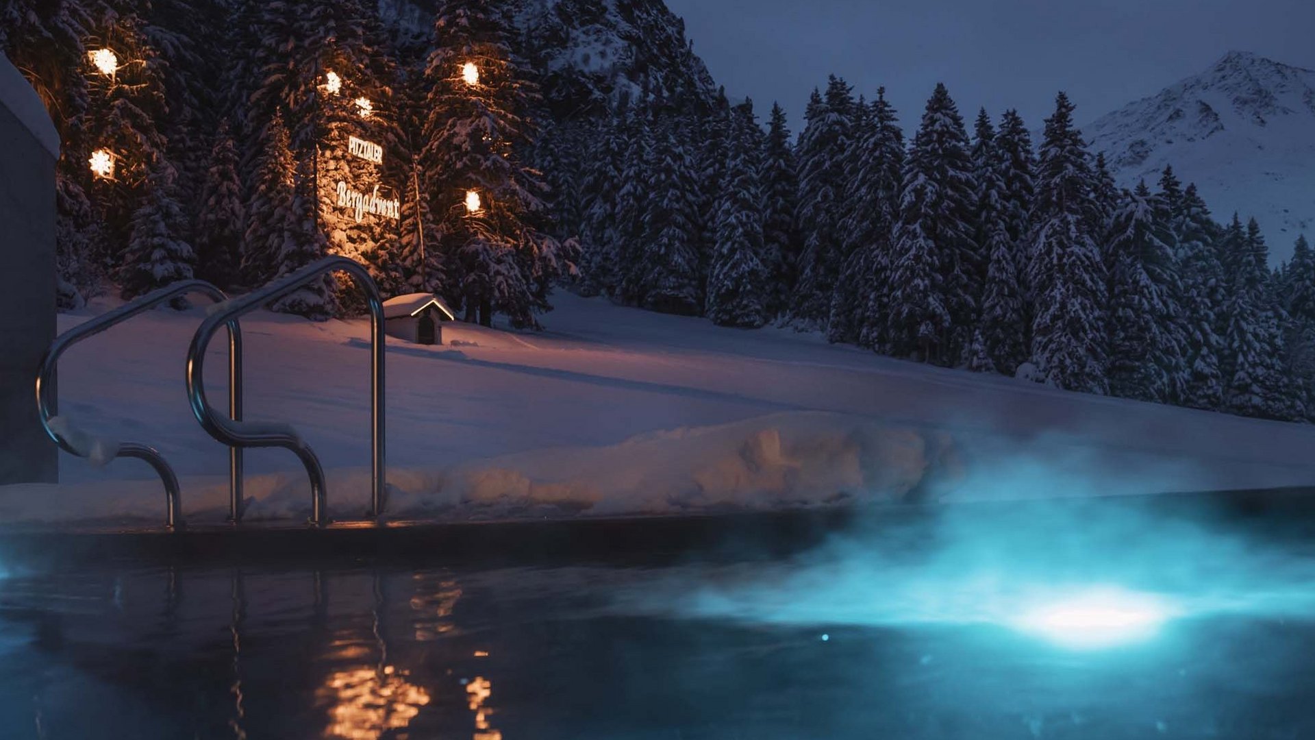 Urlaub im Pitztal? Unterkunft mit Pep! Beleuchteter Außenpool bei Nacht in verschneiter Berglandschaft