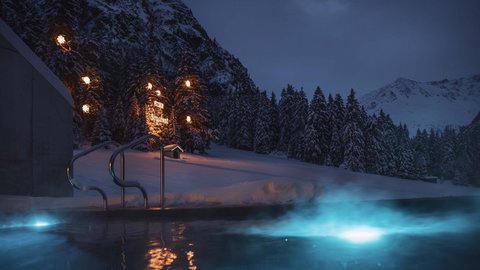 Pictures from Sportalm Lit outdoor pool at night in snowy mountain landscape