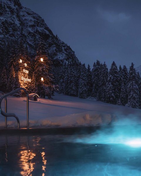 Bilder aus der Sportalm Beleuchteter Außenpool bei Nacht in verschneiter Berglandschaft