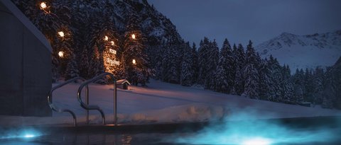 Bilder aus der Sportalm Beleuchteter Außenpool bei Nacht in verschneiter Berglandschaft