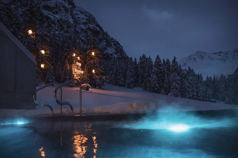 Bilder aus der Sportalm Beleuchteter Außenpool bei Nacht in verschneiter Berglandschaft