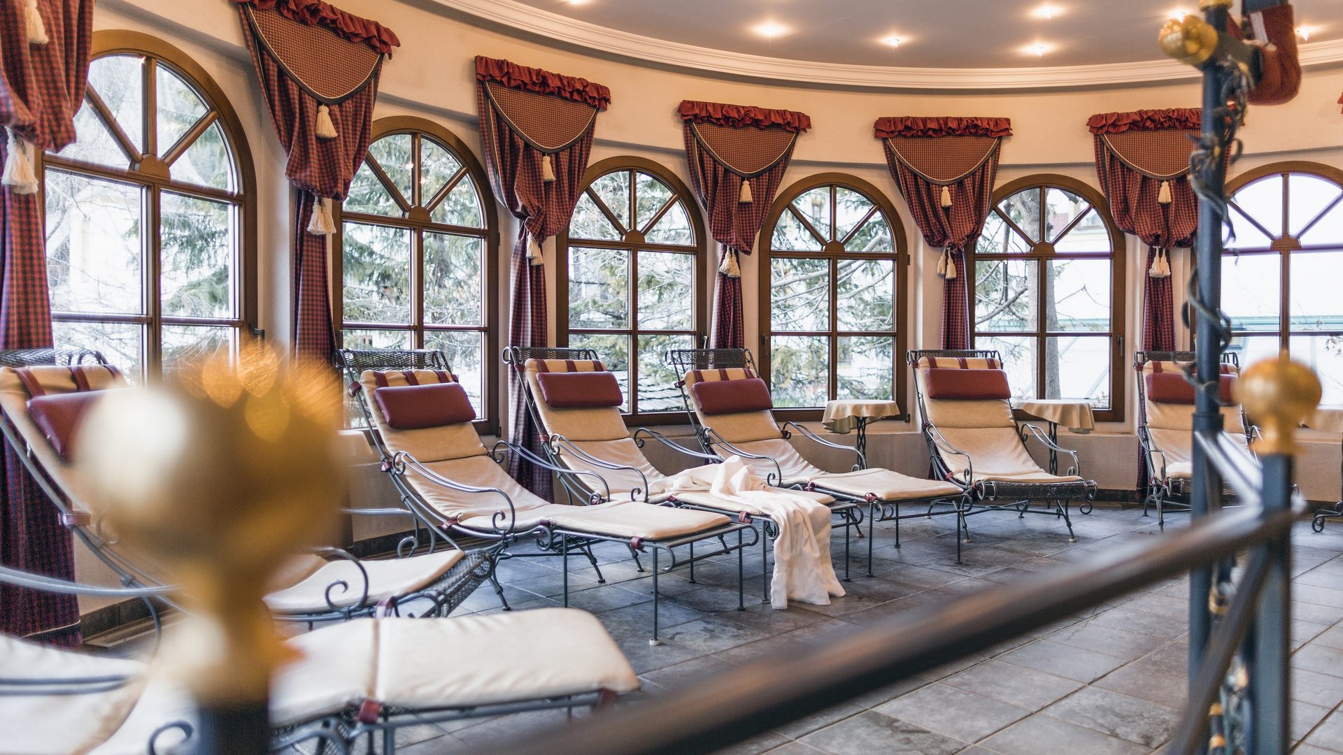 Familienurlab im Wellnessresort in Tirol Ruheliegen in einem hellen Raum mit großen Fenstern und rotem Dekor