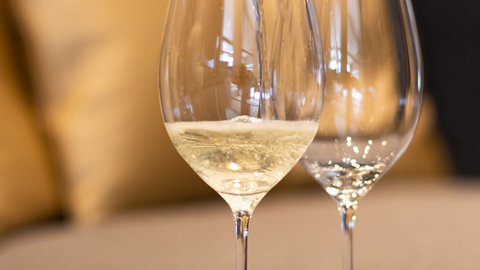 Bilder aus der Sportalm Wein wird in Weinglas eingegossen, Sofa im Hintergrund