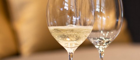 Bilder aus der Sportalm Wein wird in Weinglas eingegossen, Sofa im Hintergrund