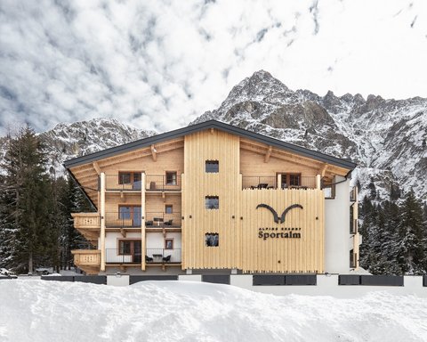 Bilder aus der Sportalm Alpenresort Sportalm vor verschneiten Bergen und Wald
