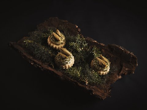 Unser Restaurant im Pitztal Drei kunstvoll dekorierte Häppchen auf Rinde und grünen Zweigen