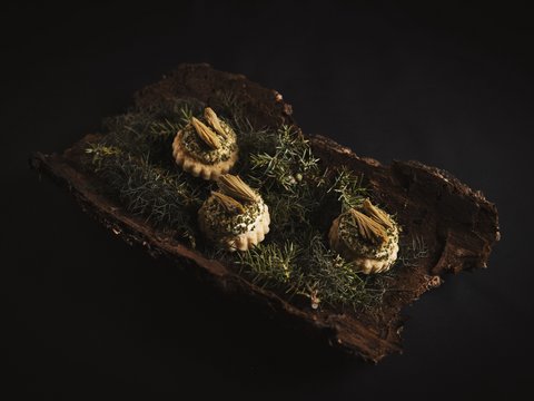 Our restaurant in Pitztal Three intricately decorated appetizers on bark and green sprigs