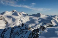 Schneebedeckte Alpen mit Skiliftstation und blauem Himmel