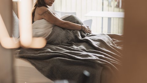 Pictures from Sportalm Woman sitting in bed with gray blanket, window view of forest