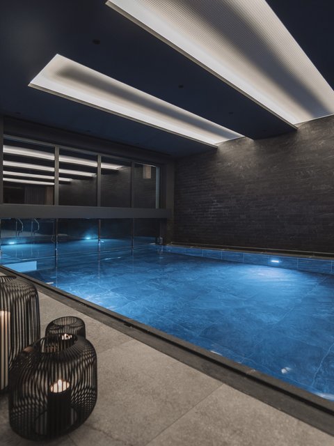 Bilder aus der Sportalm Moderner Innenpool mit blau beleuchtetem Wasser und Kerzen in Metalllaternen