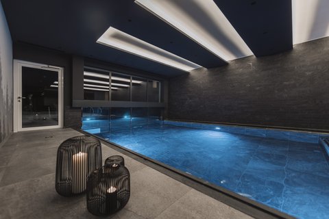 Pictures from Sportalm Modern indoor pool with blue illuminated water and candles in metal lanterns
