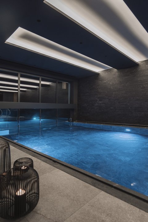 Pictures from Sportalm Modern indoor pool with blue illuminated water and candles in metal lanterns