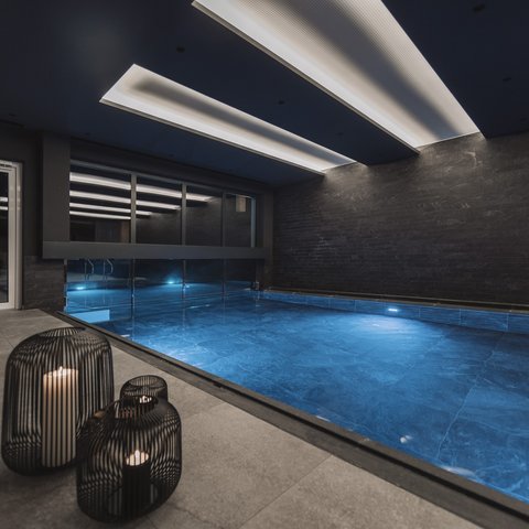 Bilder aus der Sportalm Moderner Innenpool mit blau beleuchtetem Wasser und Kerzen in Metalllaternen