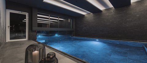 Pictures from Sportalm Modern indoor pool with blue illuminated water and candles in metal lanterns