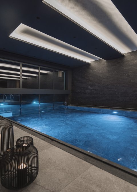Pictures from Sportalm Modern indoor pool with blue illuminated water and candles in metal lanterns