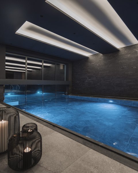 Bilder aus der Sportalm Moderner Innenpool mit blau beleuchtetem Wasser und Kerzen in Metalllaternen