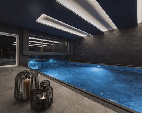 Pictures from Sportalm Modern indoor pool with blue illuminated water and candles in metal lanterns