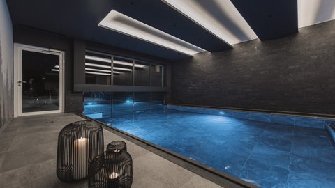 Bilder aus der Sportalm Moderner Innenpool mit blau beleuchtetem Wasser und Kerzen in Metalllaternen
