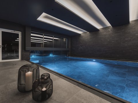 Bilder aus der Sportalm Moderner Innenpool mit blau beleuchtetem Wasser und Kerzen in Metalllaternen