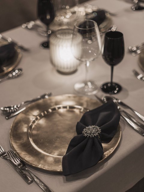 Bilder aus der Sportalm Eleganter gedeckter Tisch mit goldenem Teller, schwarzer Serviette und Kerzenlicht