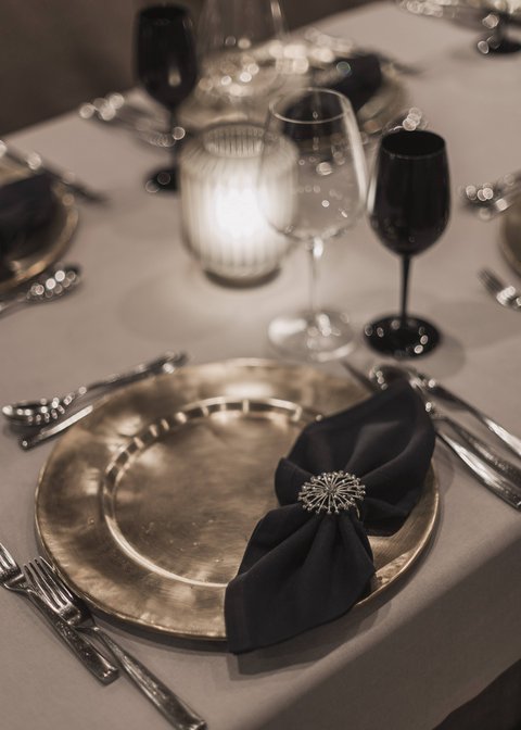 Bilder aus der Sportalm Eleganter gedeckter Tisch mit goldenem Teller, schwarzer Serviette und Kerzenlicht