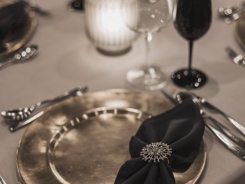 Bilder aus der Sportalm Eleganter gedeckter Tisch mit goldenem Teller, schwarzer Serviette und Kerzenlicht