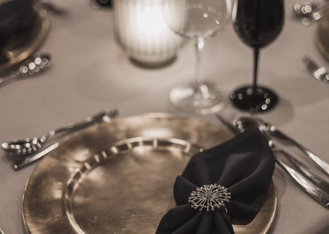 Bilder aus der Sportalm Eleganter gedeckter Tisch mit goldenem Teller, schwarzer Serviette und Kerzenlicht