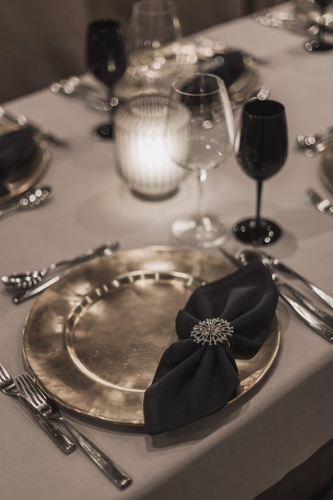 Bilder aus der Sportalm Eleganter gedeckter Tisch mit goldenem Teller, schwarzer Serviette und Kerzenlicht