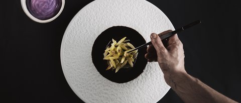 Pictures from Sportalm Hand plating fine dish with tweezers on white plate next to bowl with purple sauce